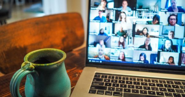 Photo d'un ordinateur portable sur une table affichant une vidéo-conférence de plusieurs personnes.